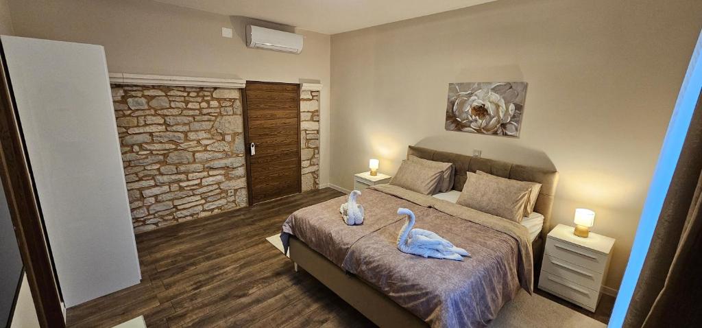 two swans sitting on a bed in a bedroom at Oliane Rooms & Accommodation in Bribir
