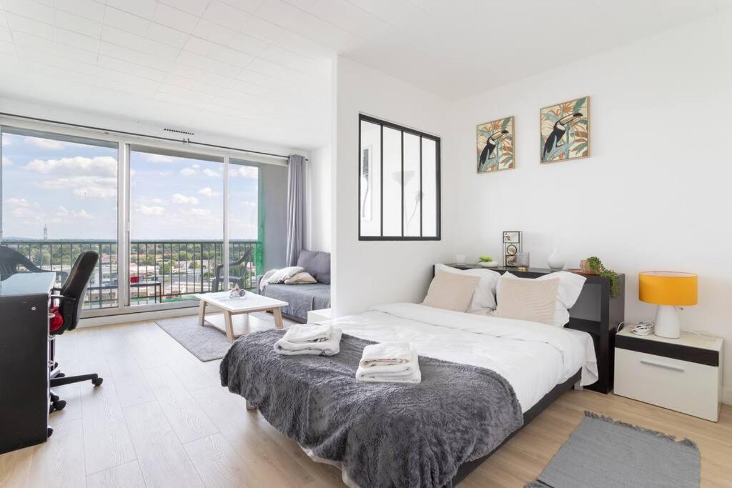 une chambre blanche avec un grand lit et un bureau dans l'établissement En hauteur - Appartement élégant proche du métro, à Mons-en-Baroeul