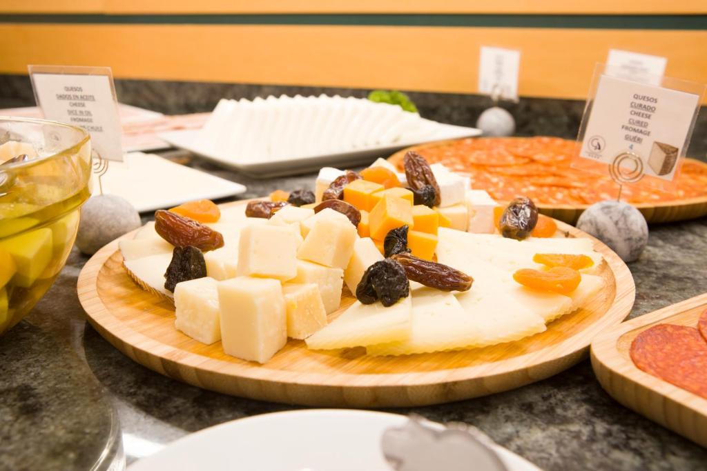 a plate of cheese and fruit on a table at Aparthotel Albufera in Alfafar