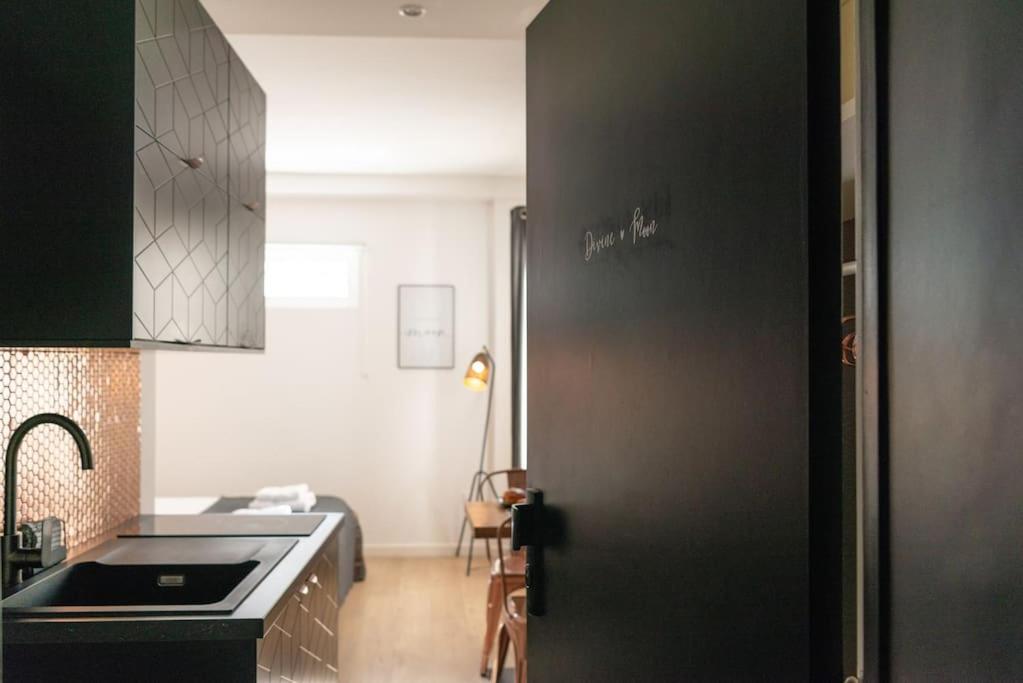 La cuisine est équipée d'un évier et d'un réfrigérateur noir. dans l'établissement Stunning studio near Canal St Martin - DIVINE MOON, à Paris