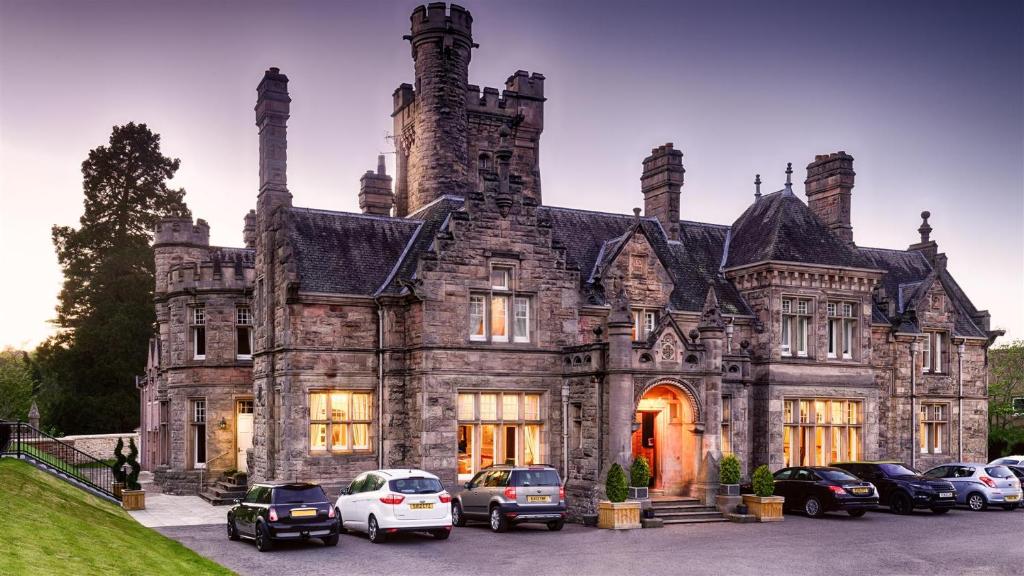 een oud huis met auto's voor het huis bij Mansion House Hotel in Elgin