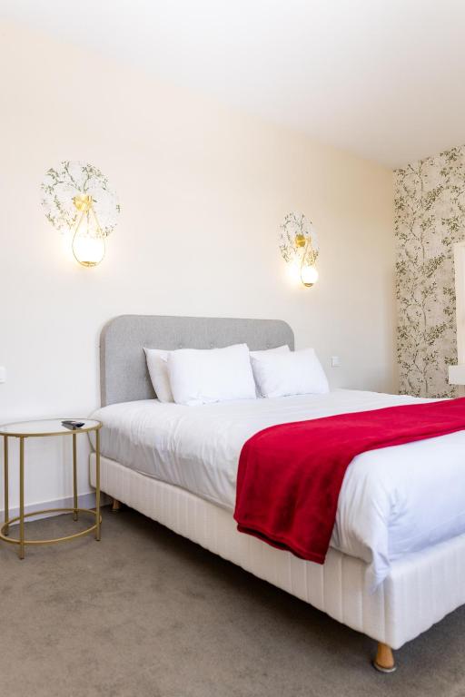 a bedroom with a large bed with a red blanket at Auberge le Prieuré des Gourmands in Vallons-de-l'Erdre