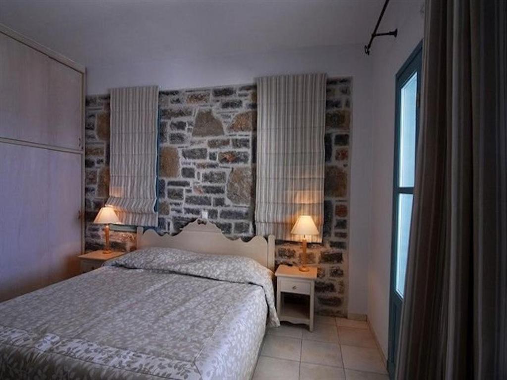 sypialnia z łóżkiem i kamienną ścianą w obiekcie Deluxe Crete Villa Villa Mousses 2 Bedroom Villa Private Pool Sea View Sitia w mieście Mochlos