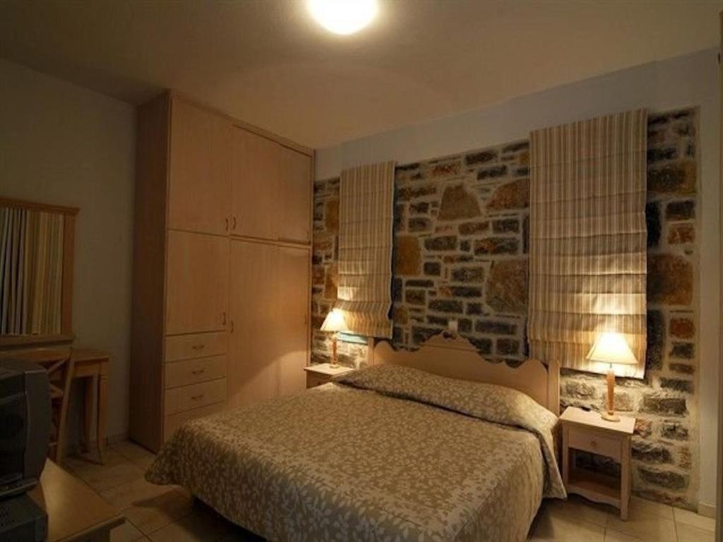 sypialnia z łóżkiem i kamienną ścianą w obiekcie Deluxe Crete Villa Villa Mousses 2 Bedroom Villa Private Pool Sea View Sitia w mieście Mochlos