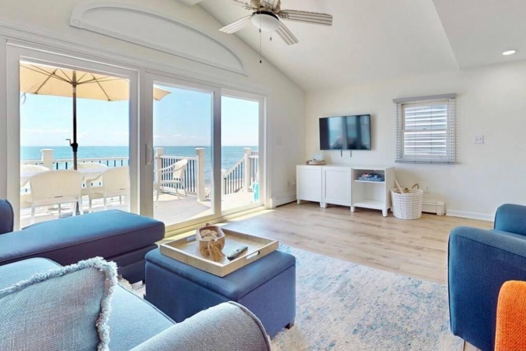 a living room with blue furniture and a view of the ocean at Charming 3 bedroom Beach Front Cottage in Milford