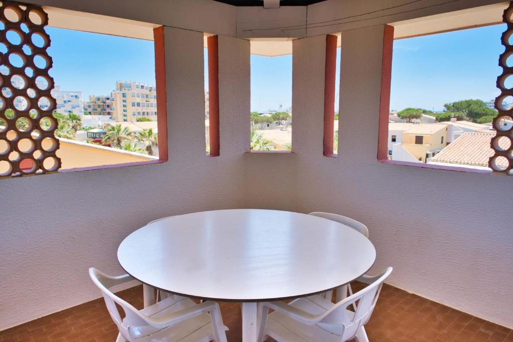 une table et des chaises blanches dans une chambre avec fenêtres dans l'établissement Nice T3 with balcony and sea view, au Barcarès
