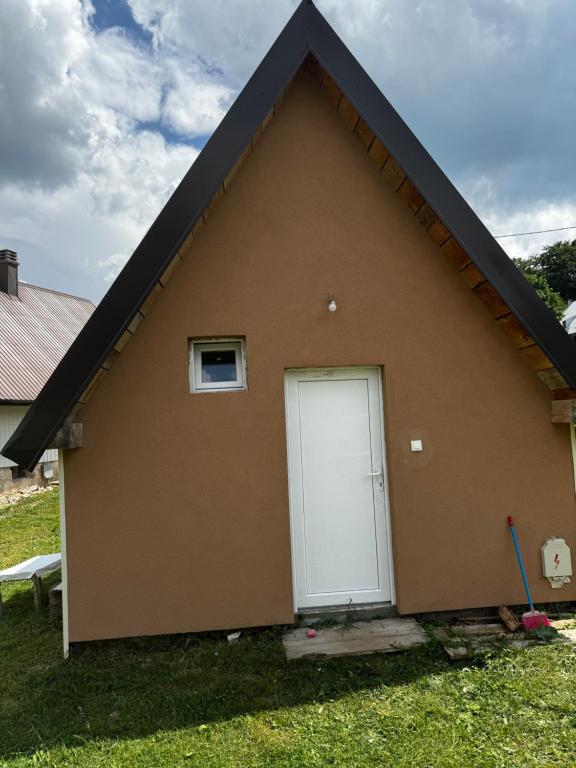a brown house with a white garage door at Apartman Jezera Village 2 in Žabljak