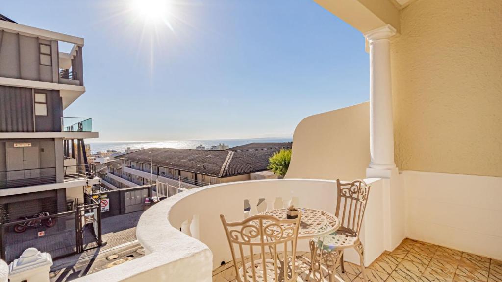 Un balcón con mesa y sillas y vista al mar. en Six Selbourne, en Ciudad del Cabo