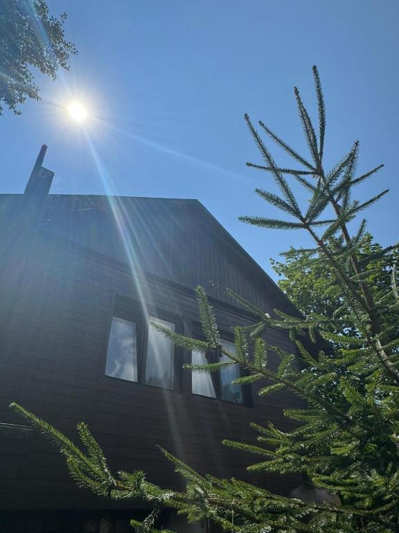 a building with the sun shining behind a tree at Chata Čertovy hlavy in Želízy