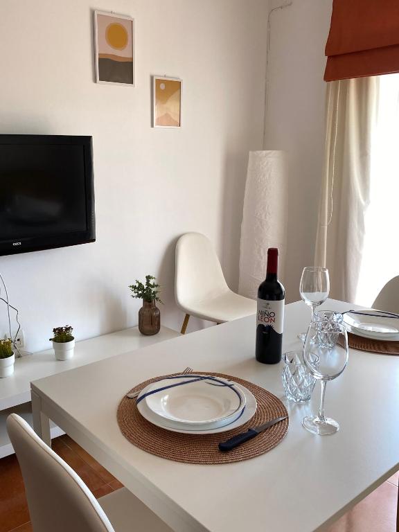 a white table with a plate and a bottle of wine at Apartamento Salas in Ronda
