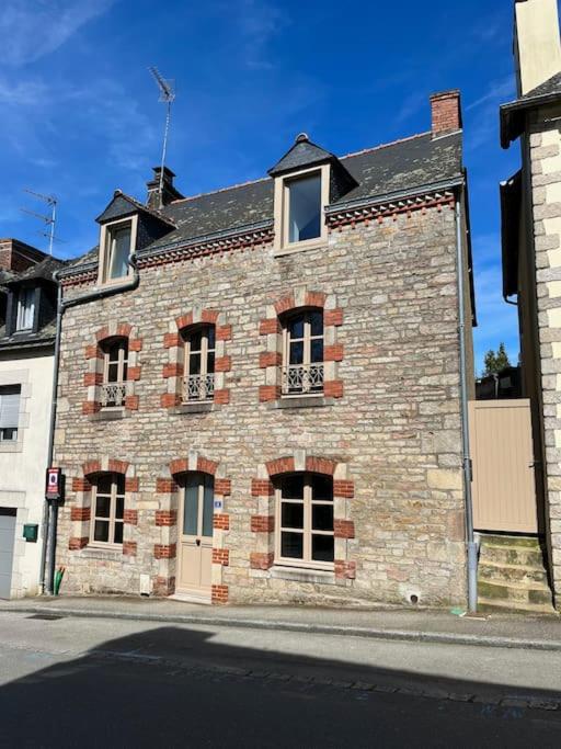 un grand bâtiment en briques sur le côté d'une rue dans l'établissement Maison de charme à Josselin, à Josselin