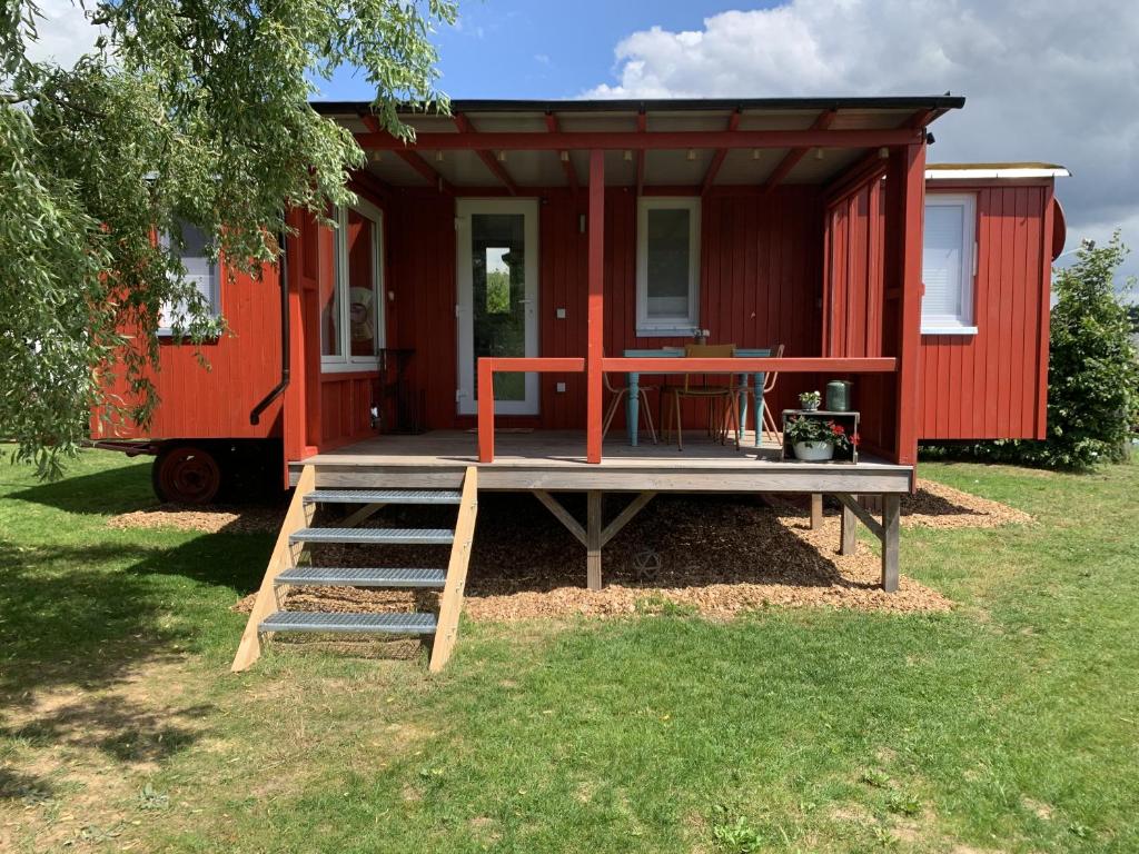 JesbergTiny House im Grünen的一座红色的小房子,甲板上配有桌子