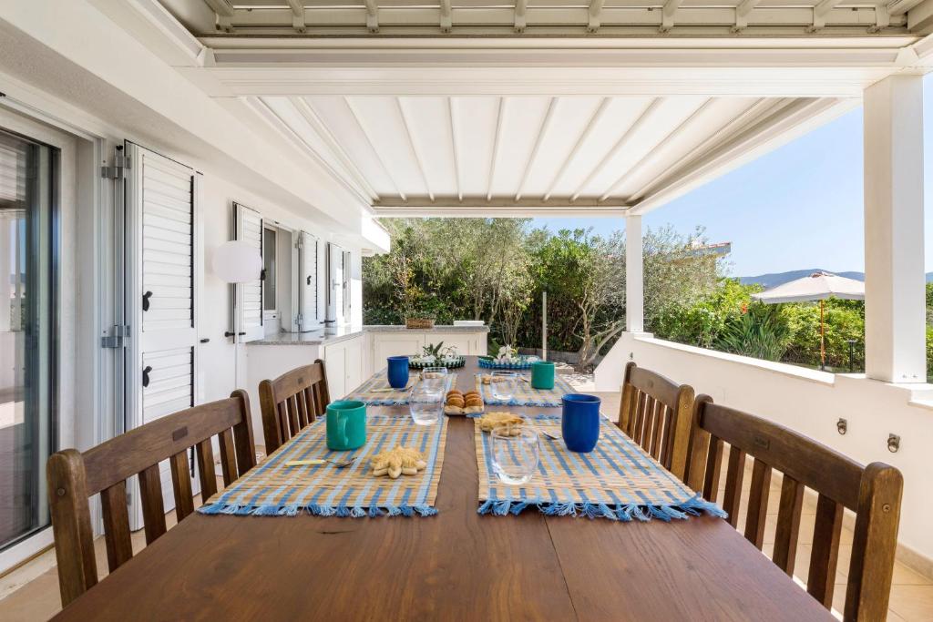 - une table sur la terrasse couverte arrière d'une maison dans l'établissement Villa Angelina con piscina e giardino privato a pochi passi dalla Spiaggia di Campus, à Villasimius