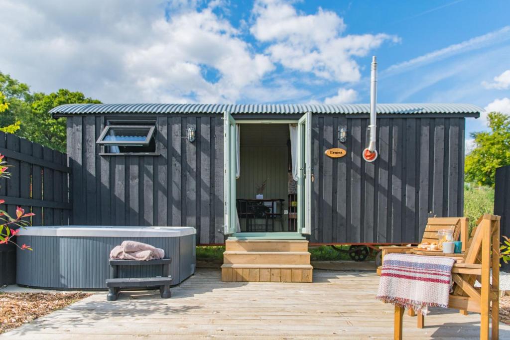 a black tiny house with a hot tub in the yard at Ernest by Bloom Stays in Tenterden