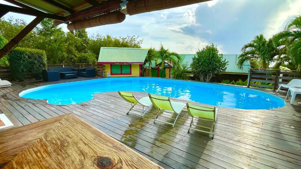 a swimming pool with chairs and a house at Gites LES CALEBASSIERS in Deshaies