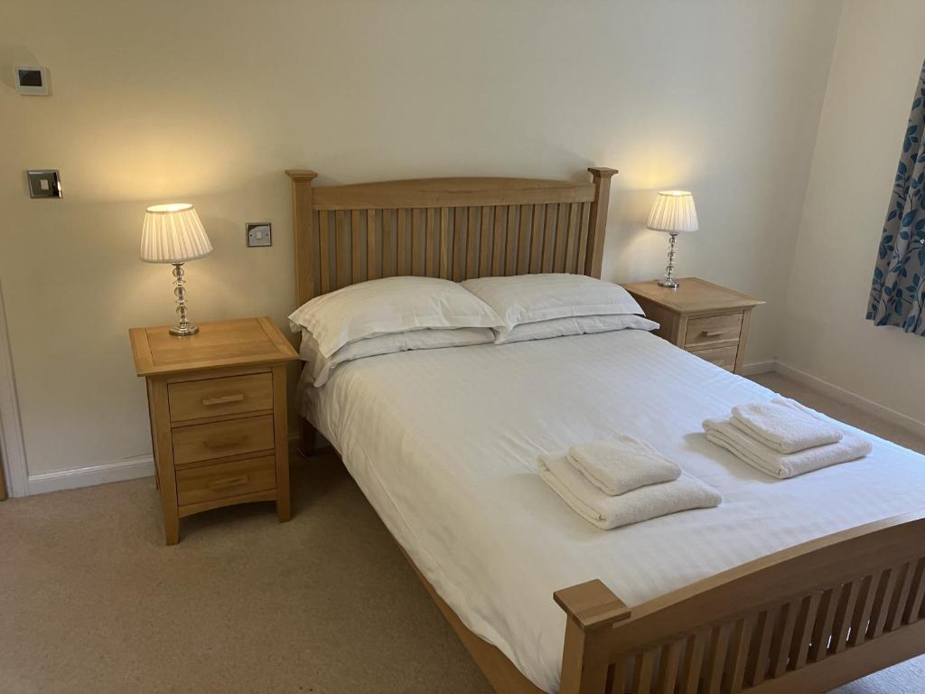 a bedroom with a large bed with two night stands and two lamps at Lake Cottage , Middleton Hall Estate in Belford