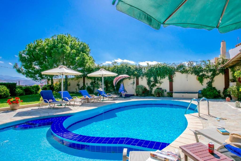 a swimming pool with blue chairs and umbrellas at Villa Agapi Episcopi in episkopi-heraklion
