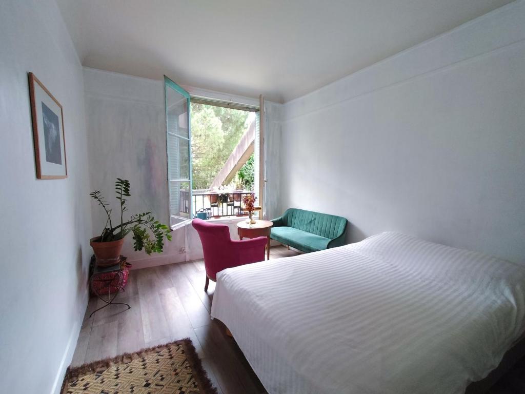 une chambre avec un lit, une chaise et une fenêtre dans l'établissement Appartement T3 lumineux et cosy, à Paris