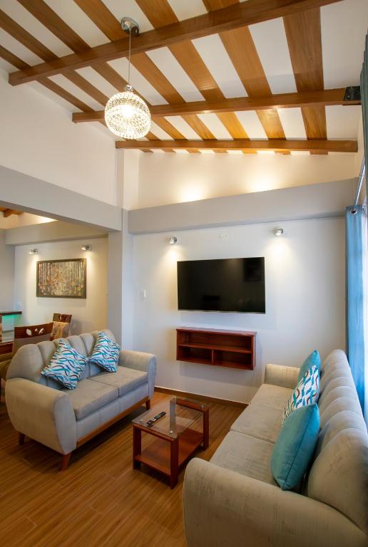 a living room with two couches and a flat screen tv at Departamento con Vista a la Ciudad in Cusco