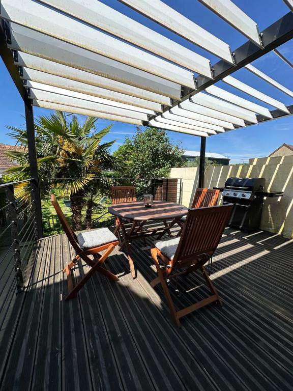 une terrasse en bois avec une table, des chaises et un grill dans l'établissement La Victoria - Charmante maison en centre ville - Gare - Jardin, au Mans