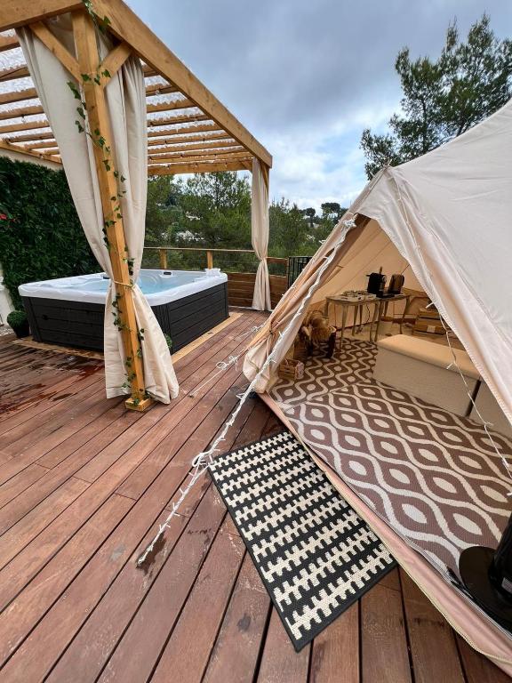 a tent on a deck with a dog laying on a rug at LOVE ROOM Tente Lodge spa MFG chez C&C, exclusivement réservée aux ADULTES in Cantaron