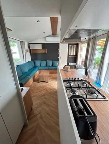 Il dispose d'une cuisine et d'un salon avec une cuisinière et un four. dans l'établissement Mobil-Home neuf Valras-Plage - Camping 4 étoiles les Sables du Midi, à Valras-Plage