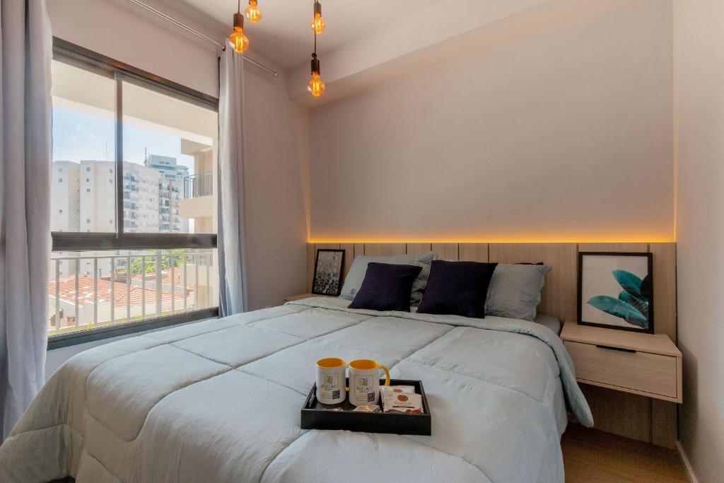 une chambre avec un grand lit et une grande fenêtre dans l'établissement Apartamentos completos ao lado do metrô, Vila Madalena, à São Paulo
