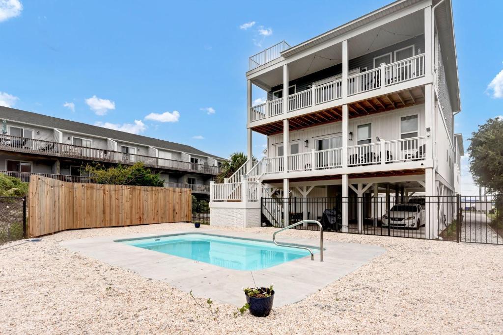 an apartment building with a swimming pool in front of a building at Seaside Serenity Beautiful Home on Topsail 7 BR in Surf City