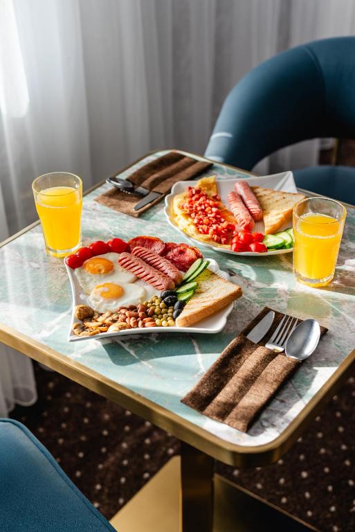a table with two plates of food and two glasses of orange juice at РИМ Grand Hotel in Almaty