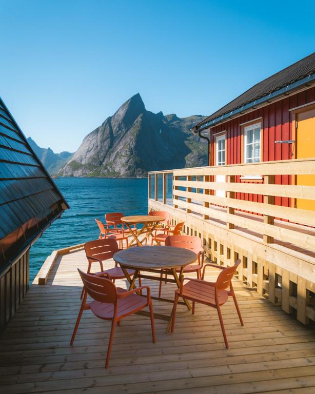 a wooden deck with tables and chairs on the water at Reinefjorden Sjøhus in Reine