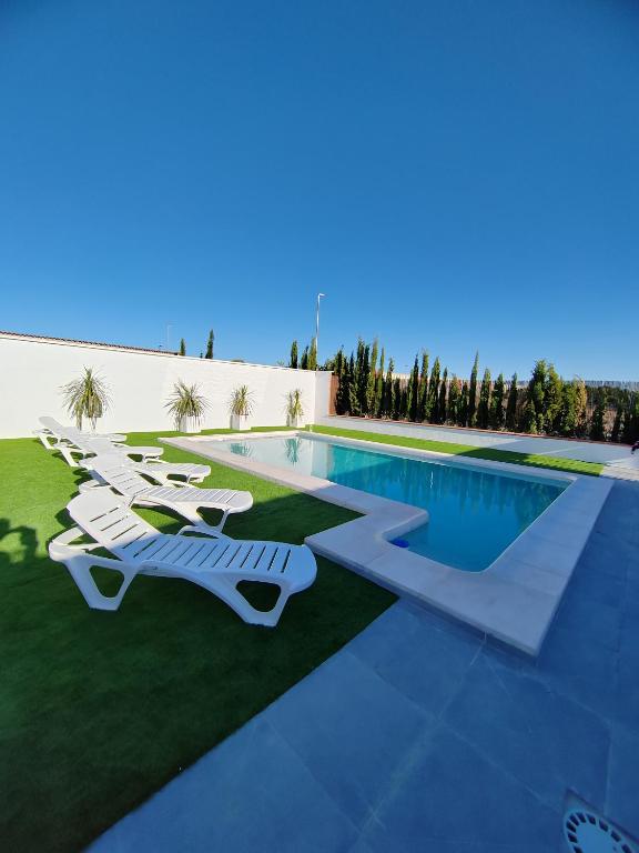 a swimming pool with lounge chairs next to a resort at Apartamentos Al Paso de Toledo, Puy du Fou a 10km in Burguillos de Toledo