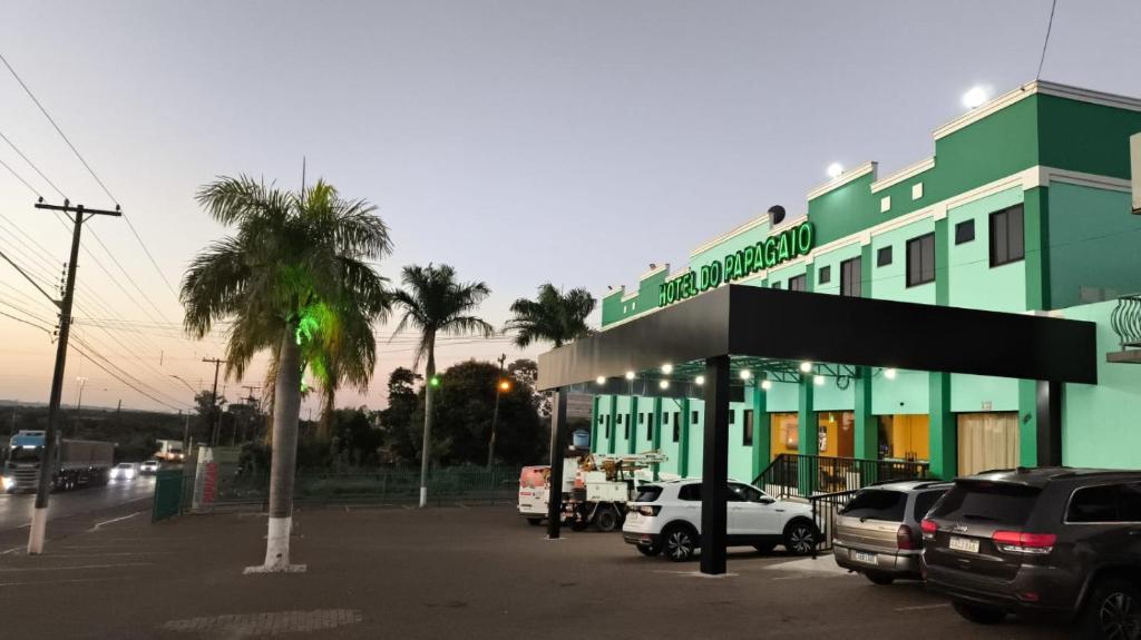 un edificio verde con coches aparcados en un aparcamiento en Papagaio Hotel, en Guaíra