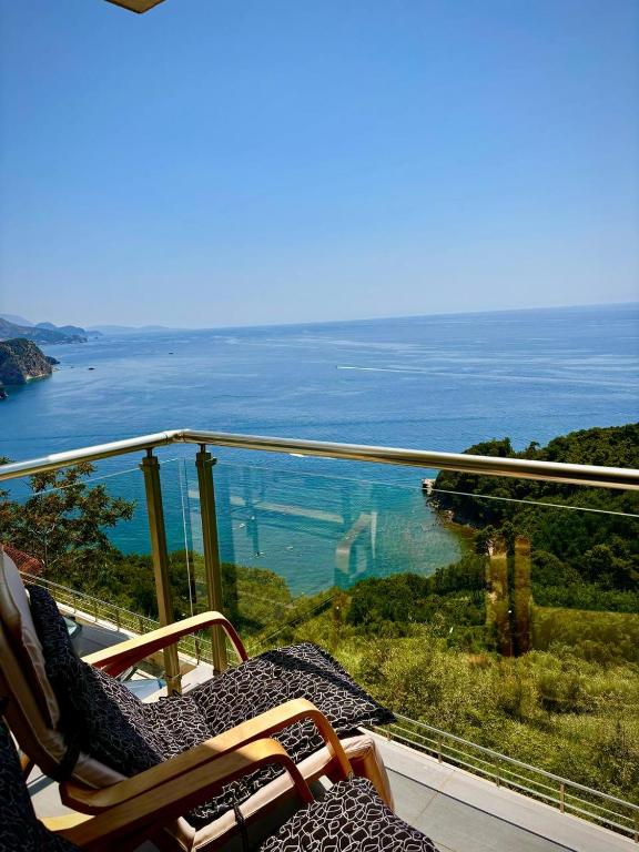 a balcony with two chairs and a view of the ocean at Romantic Hillside Escape Sea View in Budva