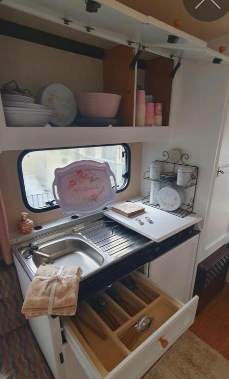 a small kitchen with a sink and dishes in it at übernachtung in unserem Wohnwagen in Gračac