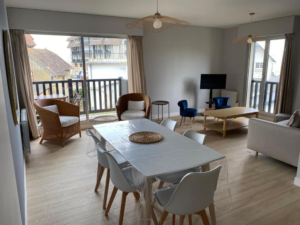 un salon avec une table et des chaises blanches dans l'établissement Appartement 65m2 avec balcon vues partielles mer à 150m de la plage et centre, wifi et parking privé, à Blonville-sur-Mer