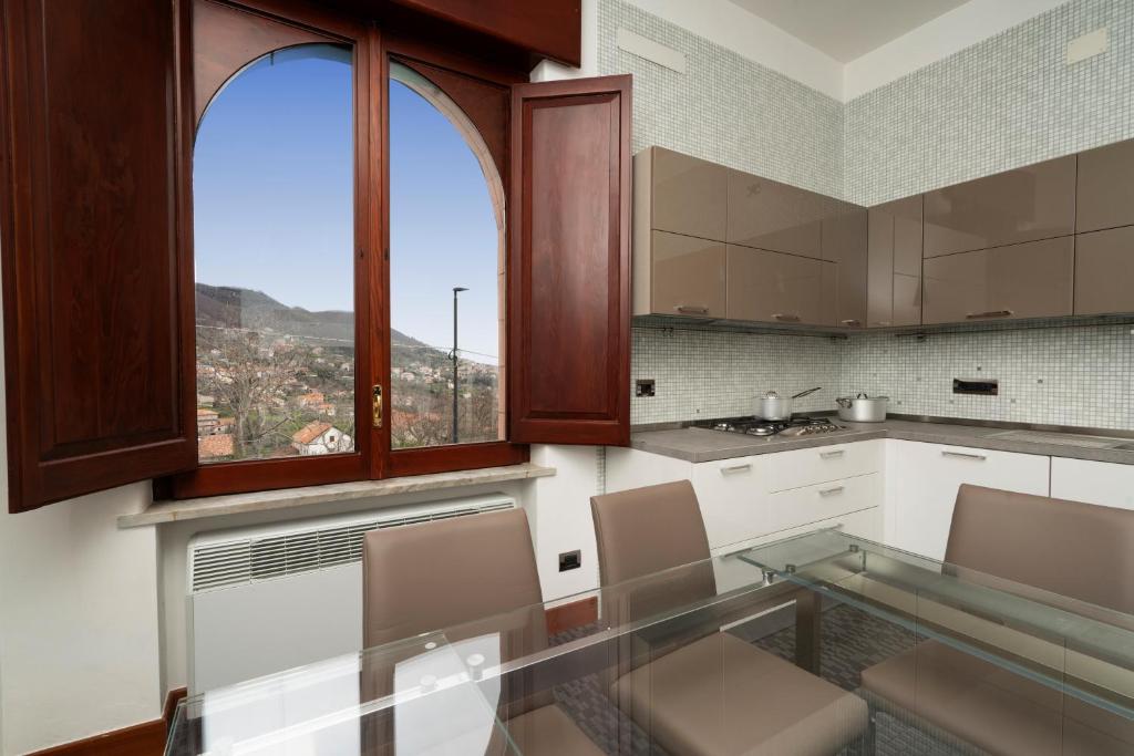 a kitchen with a glass table and two windows at ca'santoro - locazioni turistiche in Agerola