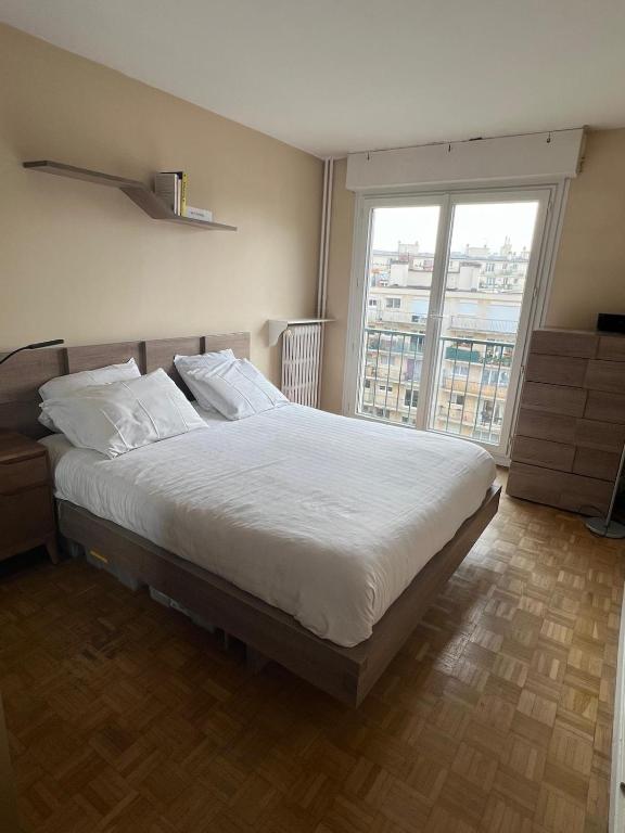 une chambre avec un grand lit avec une grande fenêtre dans l'établissement 2 Chambres Chez l'habitant à Paris Bercy - 2 Rooms in a Private Home in Paris Bercy, à Paris