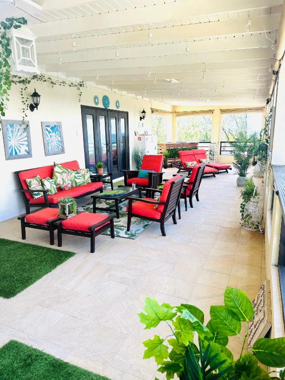 a patio with red furniture and tables and chairs at Hidden Gem Barbados in Christ Church