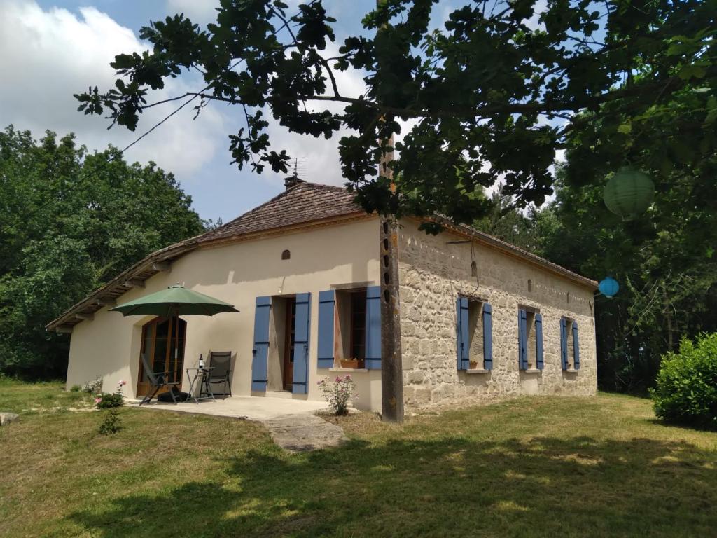une petite maison en pierre avec un parapluie vert dans l'établissement Vakantiehuis Belle Jeanne, à Saint-Colomb-de-Lauzun