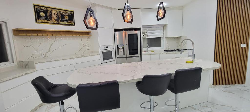 una cucina con un bancone in marmo e sedie nere di Penthouse in Ramat Gan Next to Sheba Hospital a Ramat Gan