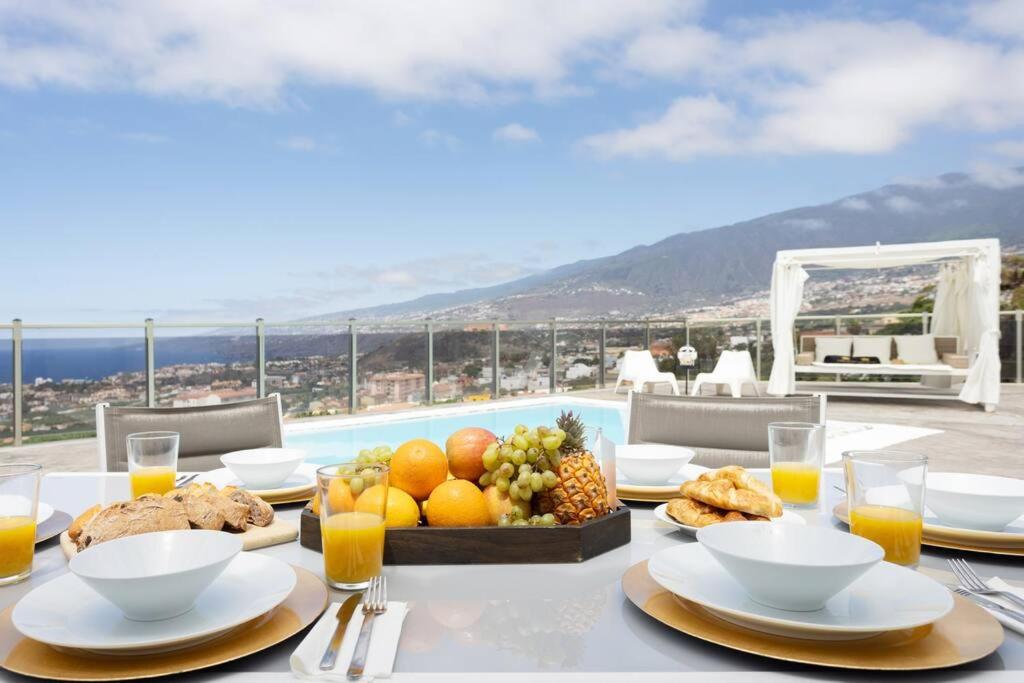 ein Tisch mit einem Tablett mit Obst und Saft auf einem Tisch in der Unterkunft Villa de lujo Concordia Piscina climatizada y excelentes vistas in Puerto de la Cruz