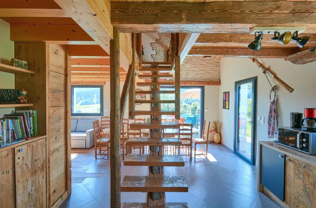 a wooden staircase in a room with a table and chairs at Le Refuge des Loups Blancs 12 pers in Ouhans