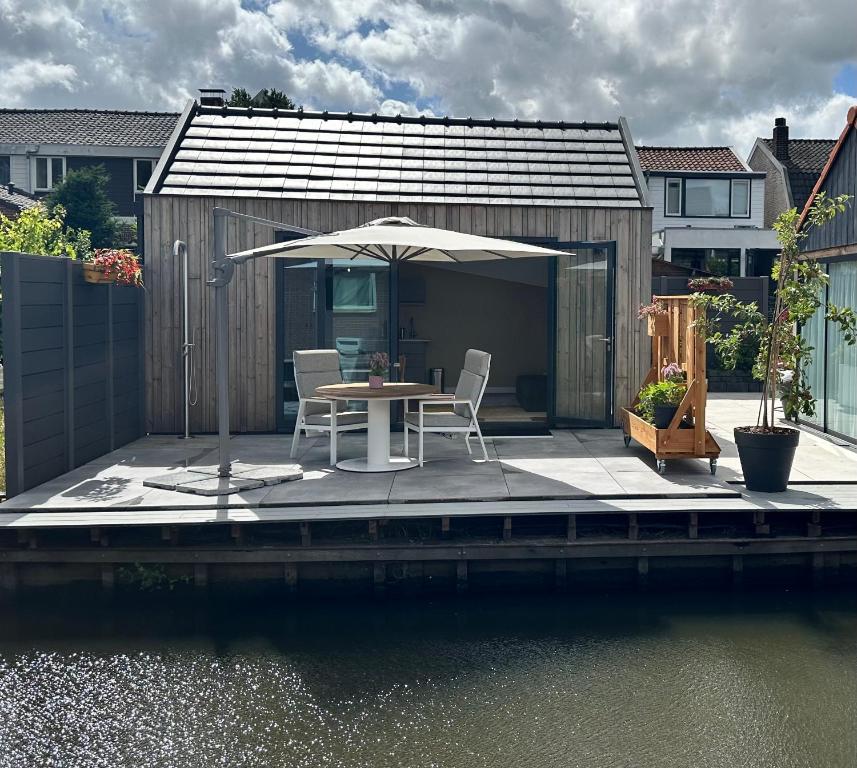 a patio with a table and an umbrella next to the water at Pakhuis Prins in Zaandam