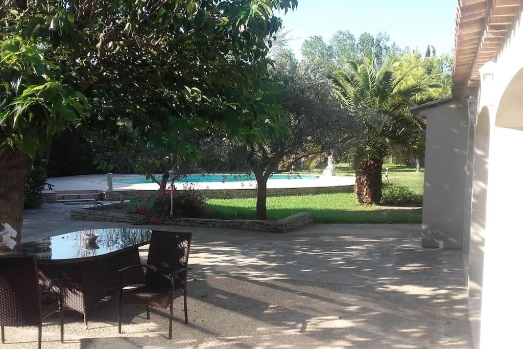 un patio avec une table et des chaises et une piscine dans l'établissement T2,PATIO avec jacuzzi,PISCINE 100m2 au pied du Luberon, à Cheval-Blanc