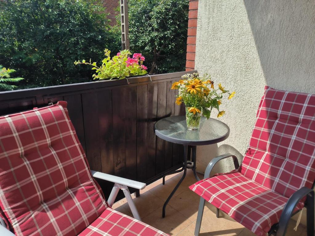 two chairs and a table with a vase of flowers on a patio at Apartament 25 Mikołajki in Mikołajki