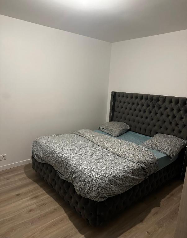 - une chambre avec un grand lit et une tête de lit rembourrée dans l'établissement Apparemment Rueil-Malmaison, à Rueil-Malmaison
