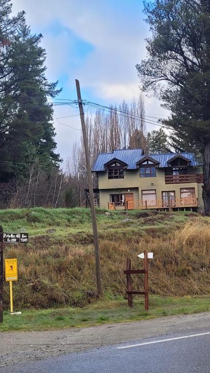 a house on the side of a hill with a street at La Margarita in El Bolsón