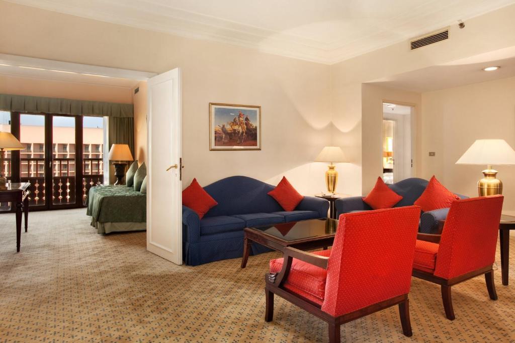 a living room with a blue couch and red chairs at Cairo World Trade Center Hotel & Residences in Cairo