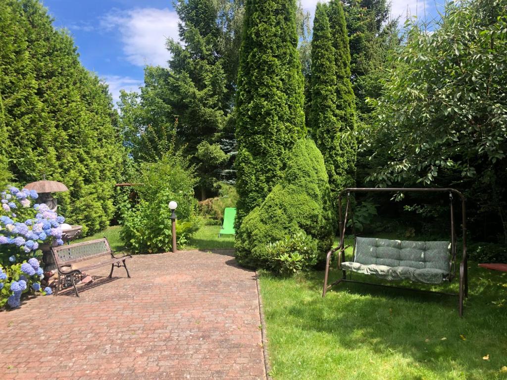 a garden with a bench and flowers and trees at "Kubania" POKOJE GOŚCINNE in Mielno