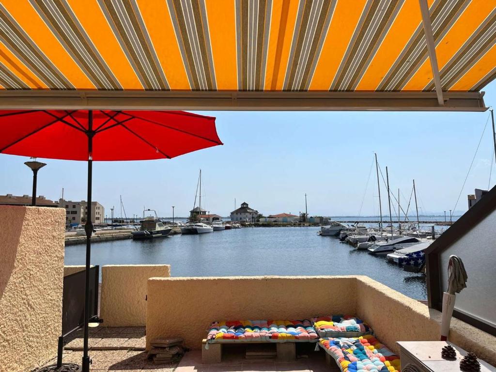 une table et un parasol sur un balcon avec une marina dans l'établissement T2 4 pers avec piscine, parking privé, clim en option - Le Barcarès - FR-1-195-95, au Barcarès